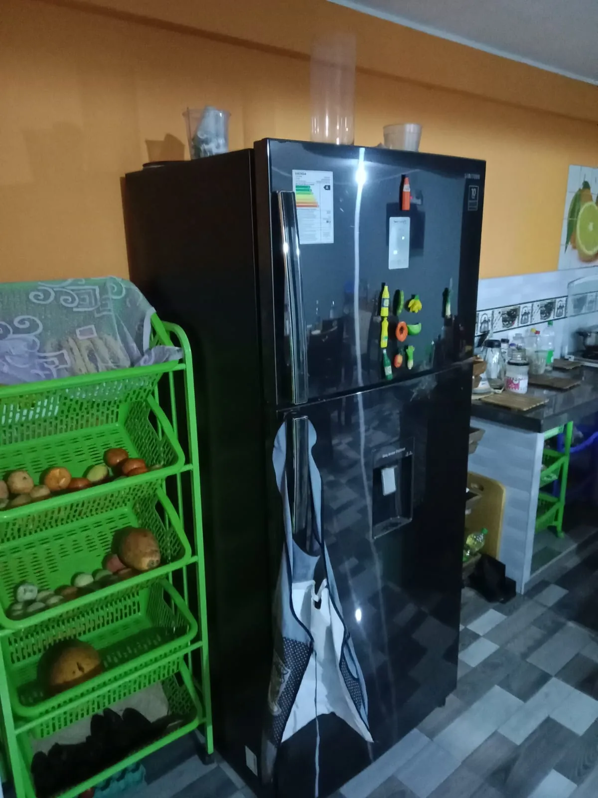 Black refrigerator with the freezer on top, standing in a home kitchen