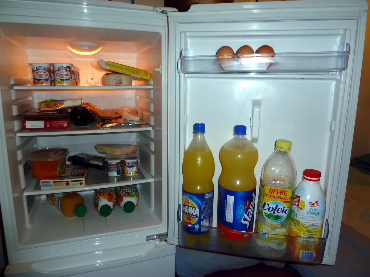 Open refrigerator with food on the shelves and bottles stored in the door