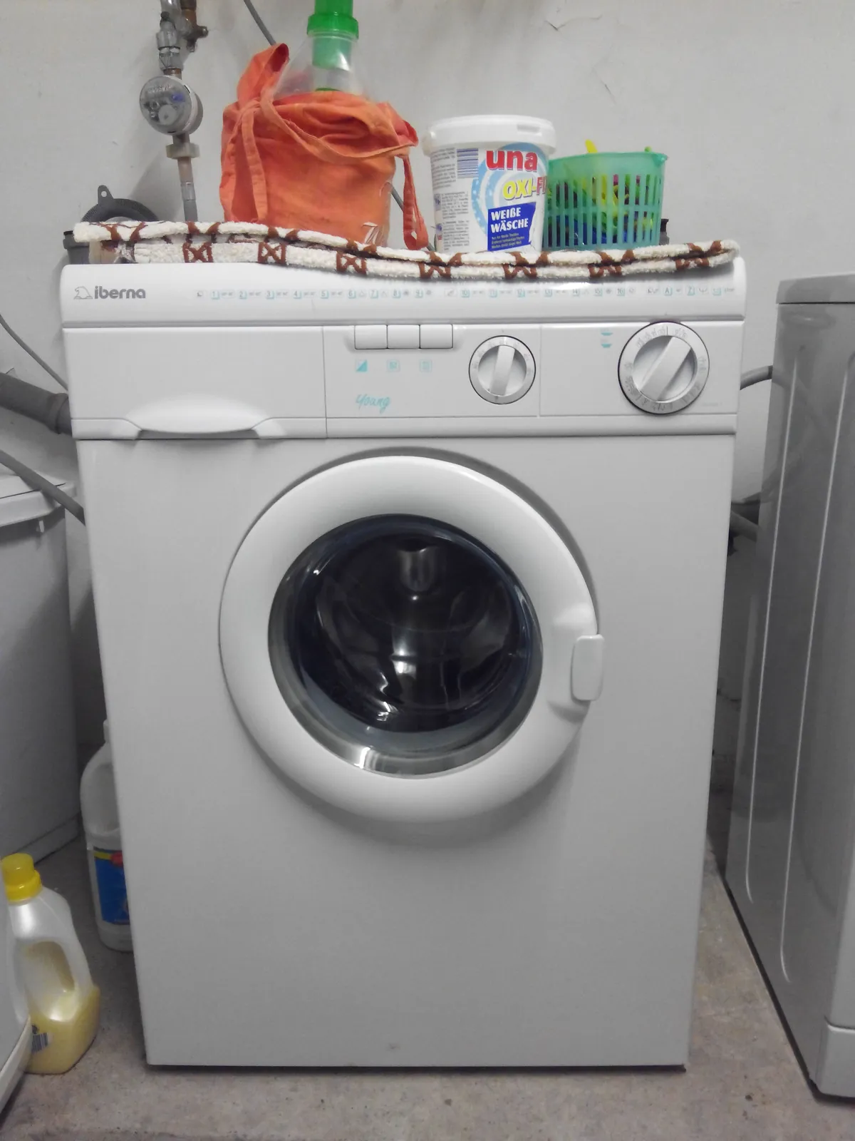 Front-load washing machine standing in a tiled laundry corner