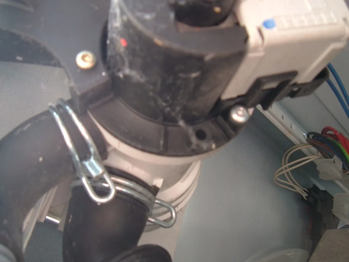 Close view of a washer drain pump with its hose held by a clamp