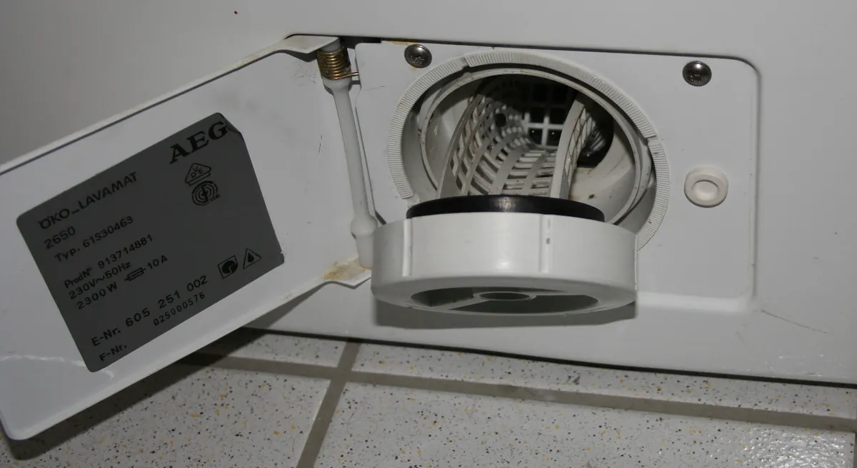 Open access flap low on a front-load washer showing the round pump filter cap